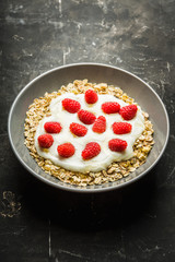 Healthy and tasty breakfast with muesli, yogurt, raspberry and honey. Selective focus. 