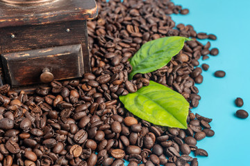 Vintage style coffee grinder and roasted coffee beans on a blue background. Close up