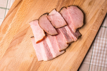 Sliced smoked boar on wooden board.