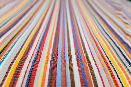 Parallel colored lines on a fabric, blurred background out of focus at the end.