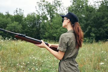 Military woman With a gun in his hands sunglasses green overalls 