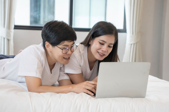 Female Couple And A Lebanese Woman Play A Social Network Together And Order Their Shopping Online With Their Laptop In Their Bedroom..LGBT And Bisexual Concept