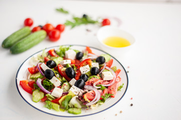 Greek vegetable salad with feta cheese and ingredients from which it is cooked on a white concrete background. Copy space.