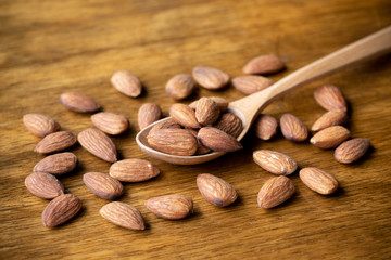 big raw peeled almonds on wooden spoon. selective focus on some almonds.