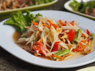Green papaya salad put peanuts long beans tomatoes and dried shrimp on white plate, Thai food