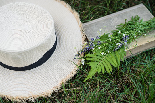 Summer flowers, old book and straw hat. relax time, summer season concept
