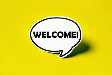 Welcome speech bubble on white paper isolated on yellow paper background with drop shadow. COPY SPACE.