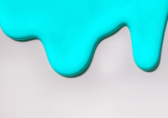 Turquoise paint spreads against a white background. Copy space.