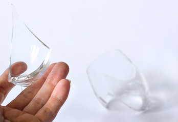 Broken glass in a female hand and shards on the background, selective focus