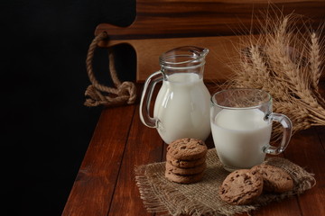 Chocolate chip cookies  with milk on rustic wooden table