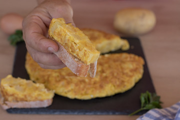 Mano cogiendo un trozo de tortilla de patatas