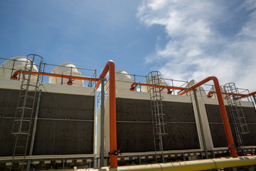 Cooling towers in data center building. Air conditioning cooling towers in front of building with fins to the front. Industrial cooling towers or air cooled water chillers with piping system.