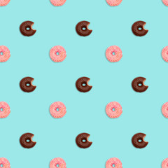 Seamless pattern with pink glazed donuts and chocolate glazed bitten donuts on pastel green background