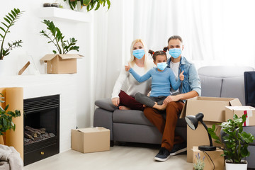 Family in medical masks on the face looks at the camera while standing in the room at home.