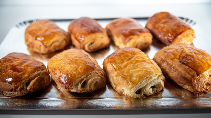
Close-up of homemade chocolate buns lined up on a silver platter