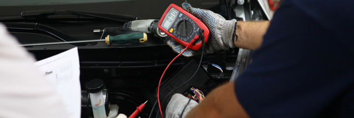 Auto mechanic in workshop with diagnose car engine. Monitoring battery voltage in real time. Cost...