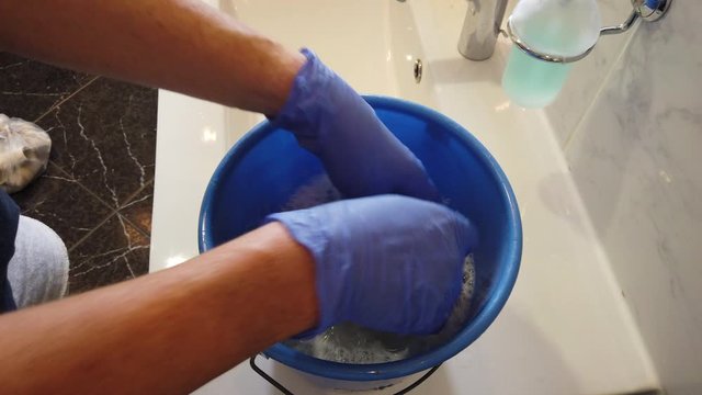 Hand mit Gummihandschuhen reinigt Bad Waschbecken Toilette WC