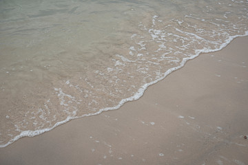 Soft ocean wave on tropical sandy beach in rainy season