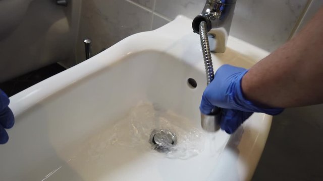 Hand mit Gummihandschuhen reinigt Bad Waschbecken Toilette WC