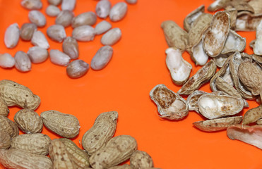 Raw peanuts top view isolated on orange plate background