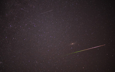 Meteor shower during perseid curent. Andromeda galaxy in night sky