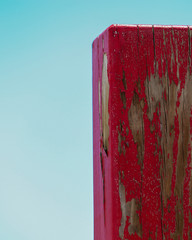 Red chipped painted beach wood against blue back round