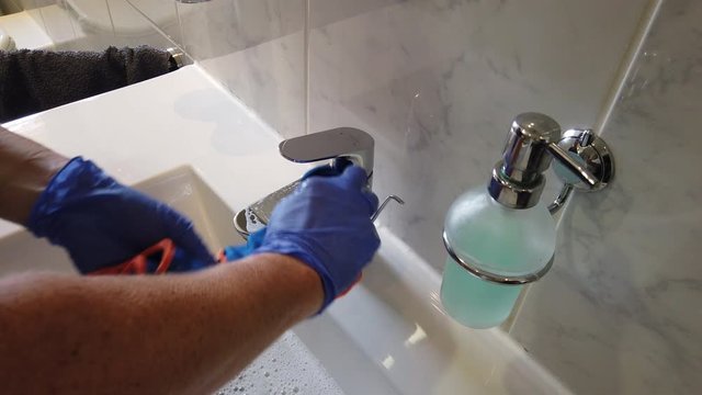 Hand mit Gummihandschuhen reinigt Bad Waschbecken Toilette WC