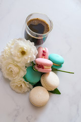 Fototapeta na wymiar Colourful macaroons Colourful macaroons are laying on the table along with the coffee in transparent cup and white roses, breakfast time. High quality photocoffee white roses,