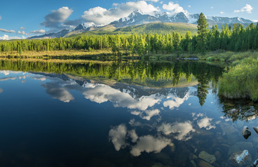 Picturesque mountain lake in the summer morning, Altai. Beautiful reflection of mountains, sky and white clouds.