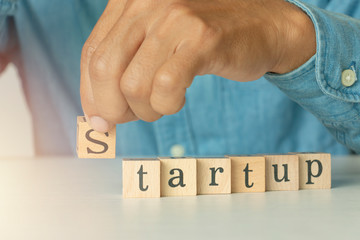 Man hand holding wooden cube with start up word on table, concept emerging leadership success.