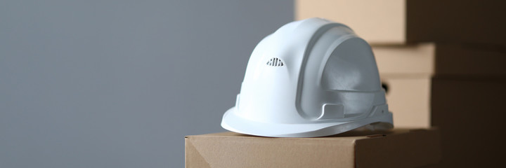 Fototapeta premium Close-up of cardboard boxes for delivery. White helmet lying on boxes. Empty place for text for design in right side. Isolated on grey. Package and relocation concept