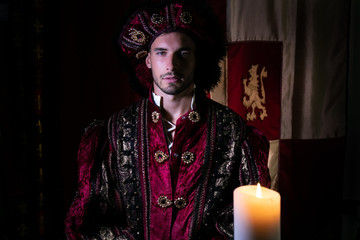 Portrait of handsome king with beard dressed in costume looking at camera with candle in foreground