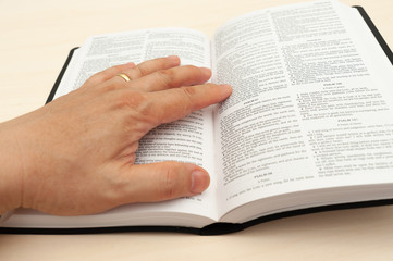 Hands on the Holy Bible in close-up. Studying and reading the Word of God. Top view
