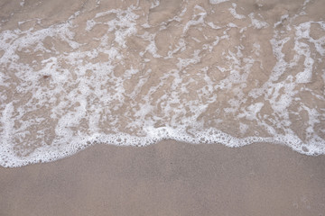 Soft ocean wave on tropical sandy beach in rainy season