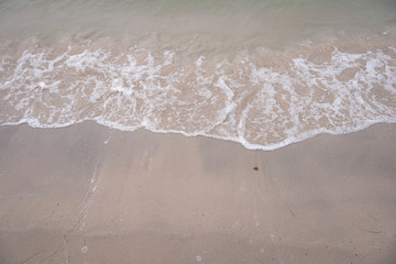 Soft ocean wave on tropical sandy beach in rainy season