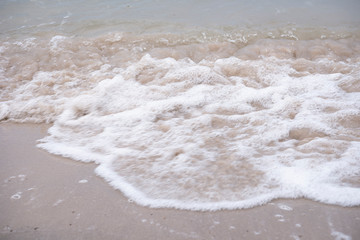 Soft ocean wave on tropical sandy beach in rainy season