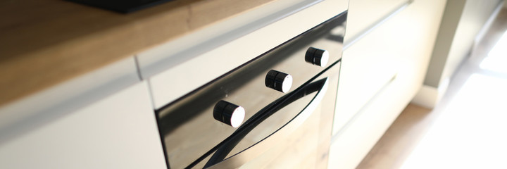 Close-up of modern luxury black cookstove embedded in kitchen table. Rays of sun on kitchenware....