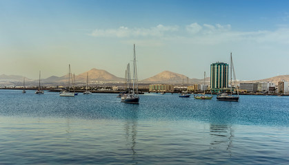 Moored yachts in the bay in Arrecife, Lanzarote with the volcanic landscape as a backdrop on a sunny afternoon