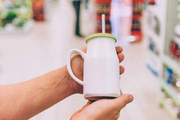 A man in a supermarket holds a cup with a straw for a drink.