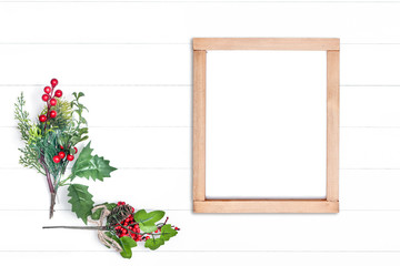 Vertical wooden frame and branches of greenery with red berries