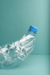 Part of the used crushed plastic bottle on the blue background. Recycling concept.