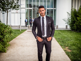 Portrait of stylish young man wearing business suit, standing in modern city setting