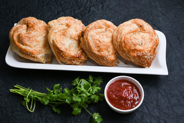 Fast food many chicken puffs, pattie pastries, popular bakery snacks with tomato sauce or ketchup in Kerala India. Indian food cut and being served using server.