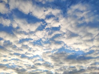 The sun shines on the clouds in the sky. Blue sky with clouds background.