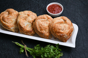 Fast food many chicken puffs, pattie pastries, popular bakery snacks with tomato sauce or ketchup in Kerala India. Indian food cut and being served using server.