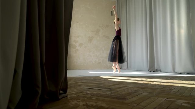 Dancing in pointe shoes on the tiptoes, female dancer does ballet exercises, ballet rehearsal, ballerina does dance steps, dance studio lesson. Ballerina silhouette disappears behind the curtain.