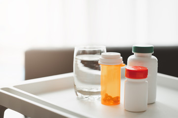 Bottle of medicine and glass of water on table in living room
