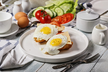 Fried eggs with cheese and tomatoes on a croissant on a white plate. Morning food still life. Tasty breakfast
