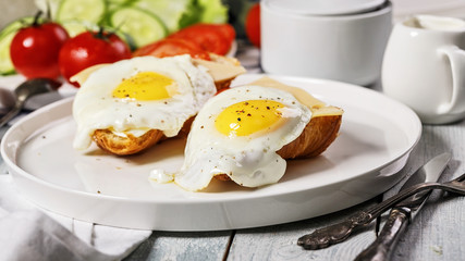 Food banner format. Fried eggs with cheese and tomatoes on a croissant on a white plate. Morning still life. Tasty breakfast