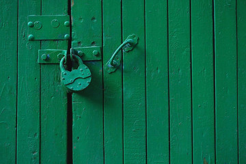 Old metal padlock on wooden green door background. template for design